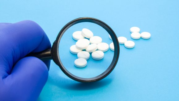 Pharmacist or expert on pharmaceutical inspection identifies pills. Testing, verification and determining pharmaceutical counterfeiting or fakes of medicines and medicinal substance quality concept