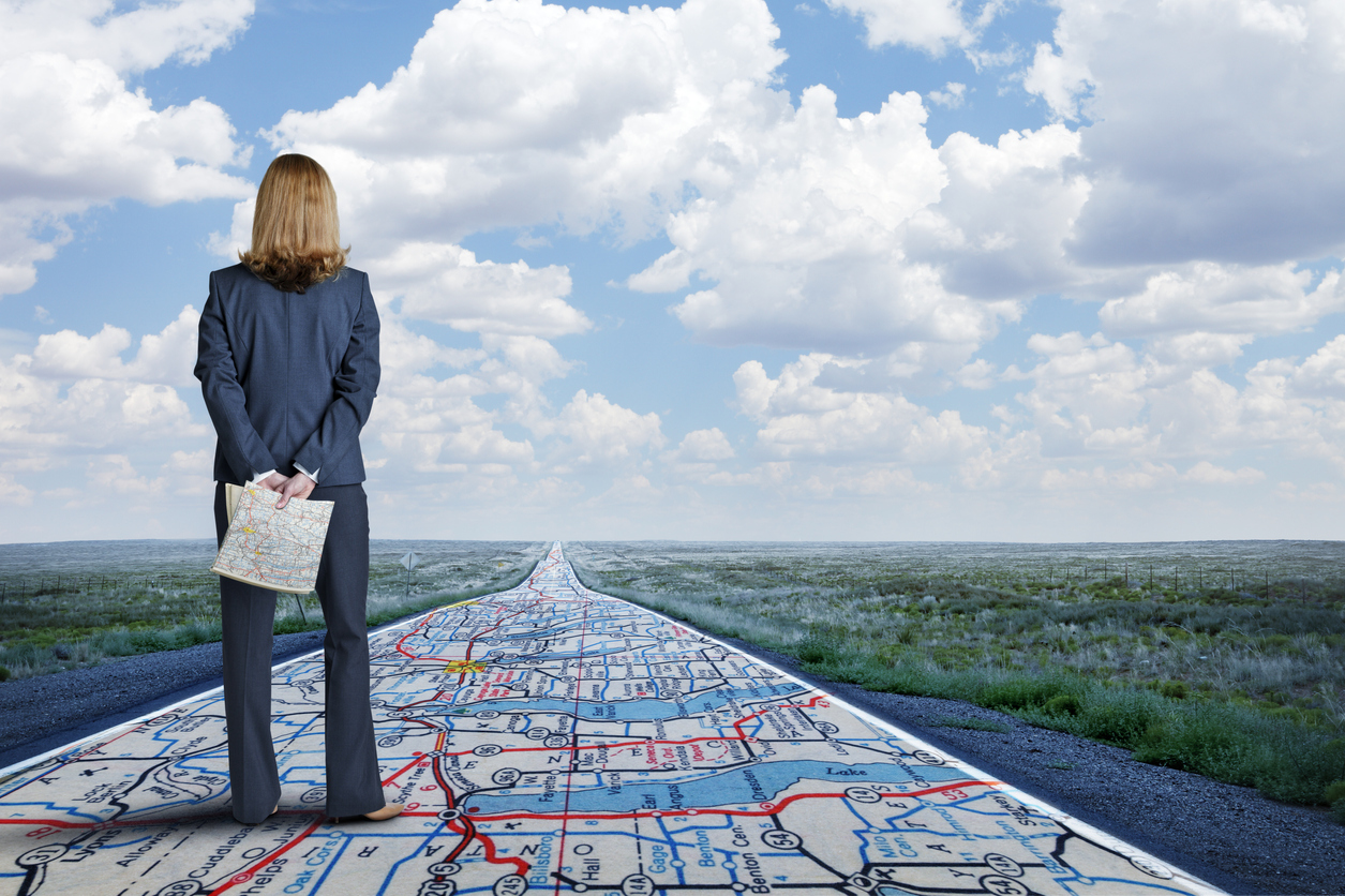 Businesswoman Stands On Long Road With Road Map Painted On It