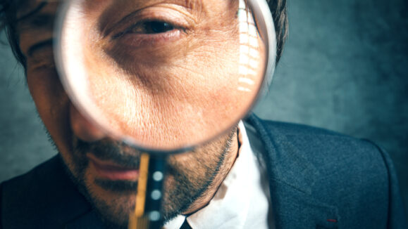 Enlarged,Eye,Of,Tax,Inspector,And,Financial,Auditor,Looking,Through